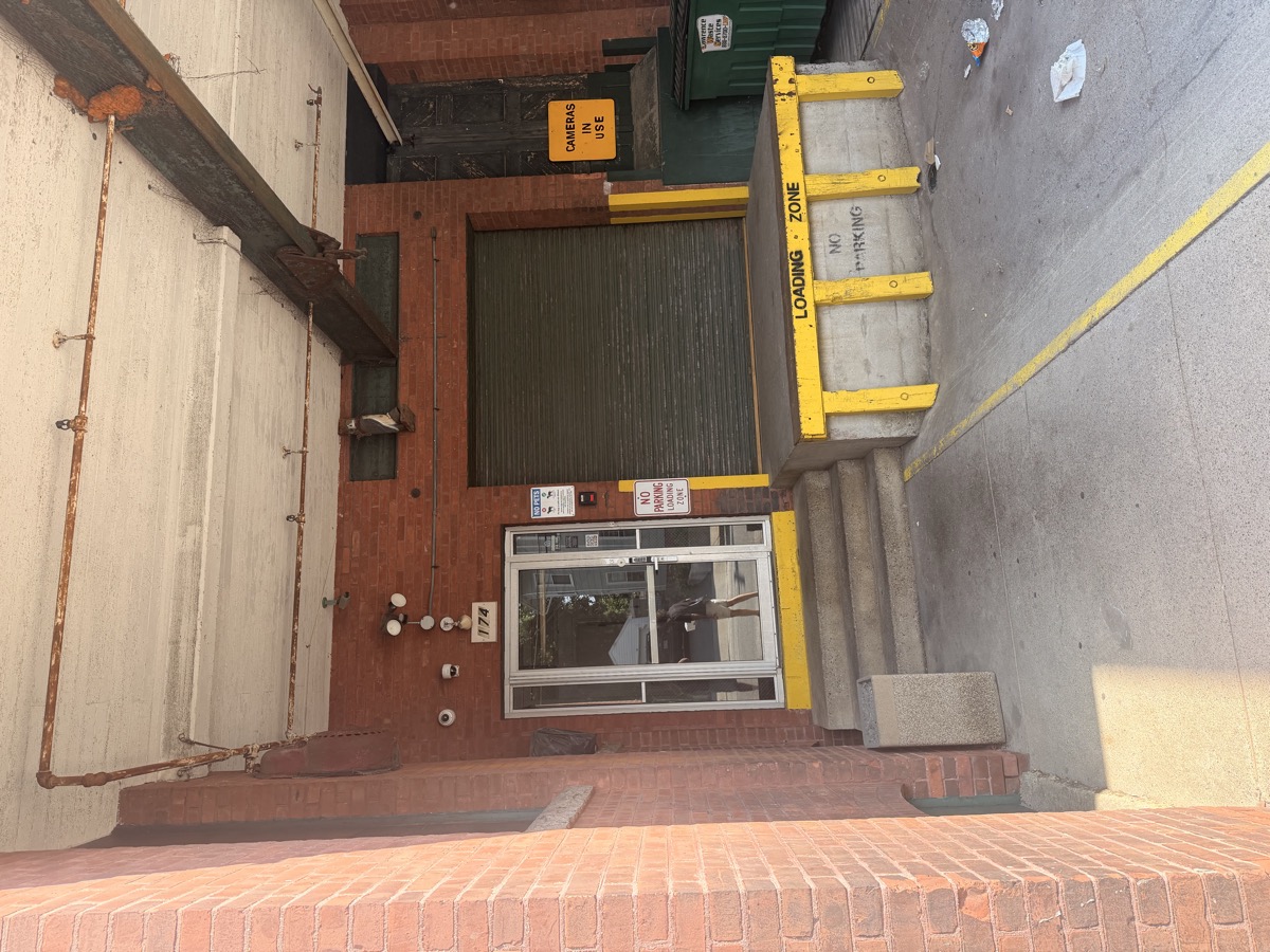 The studio's main entrance: a glass door marked 174, directly beside the concrete loading dock painted Loading Zone, No Parking.
